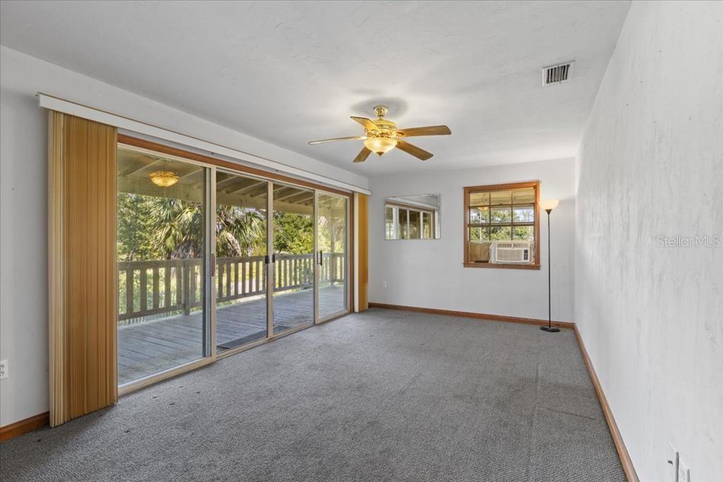 16791 Sandra Street Cedar Key, FL 32625 - Photo 30 of 50 an empty room with windows and ceiling fan
