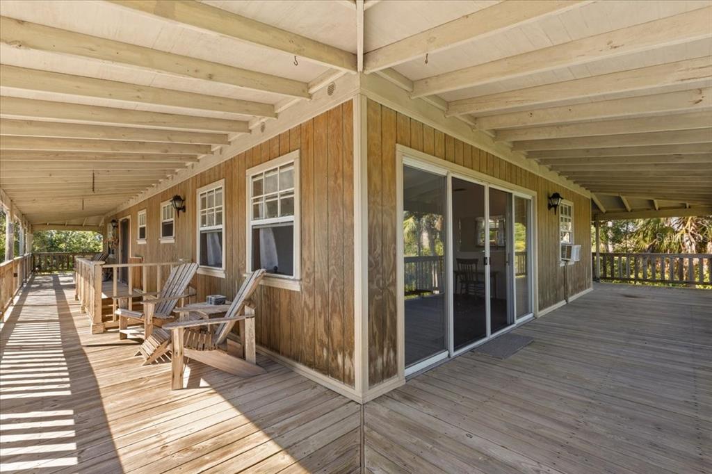16791 Sandra Street Cedar Key, FL 32625 - Photo 37 of 50 a view of a patio with table and chairs with wooden floor and floor to ceiling window