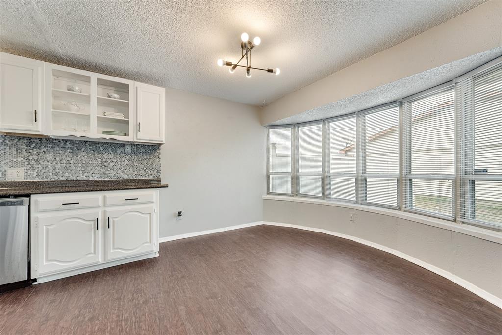 711 Valley Hill Road Duncanville, TX 75137 - Photo 9 of 20 a view of an empty room with a kitchen and wooden floor