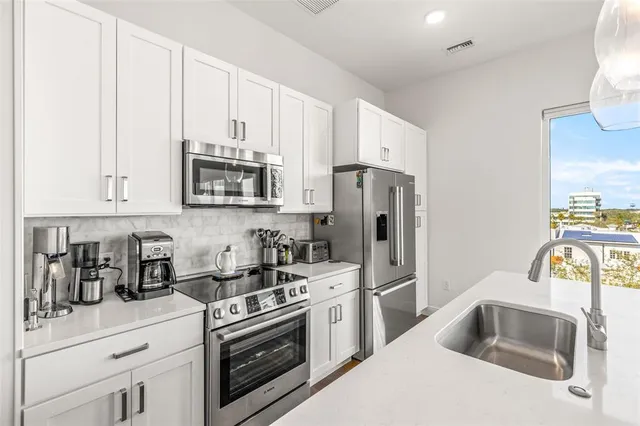 a kitchen with white cabinets and stainless steel appliances