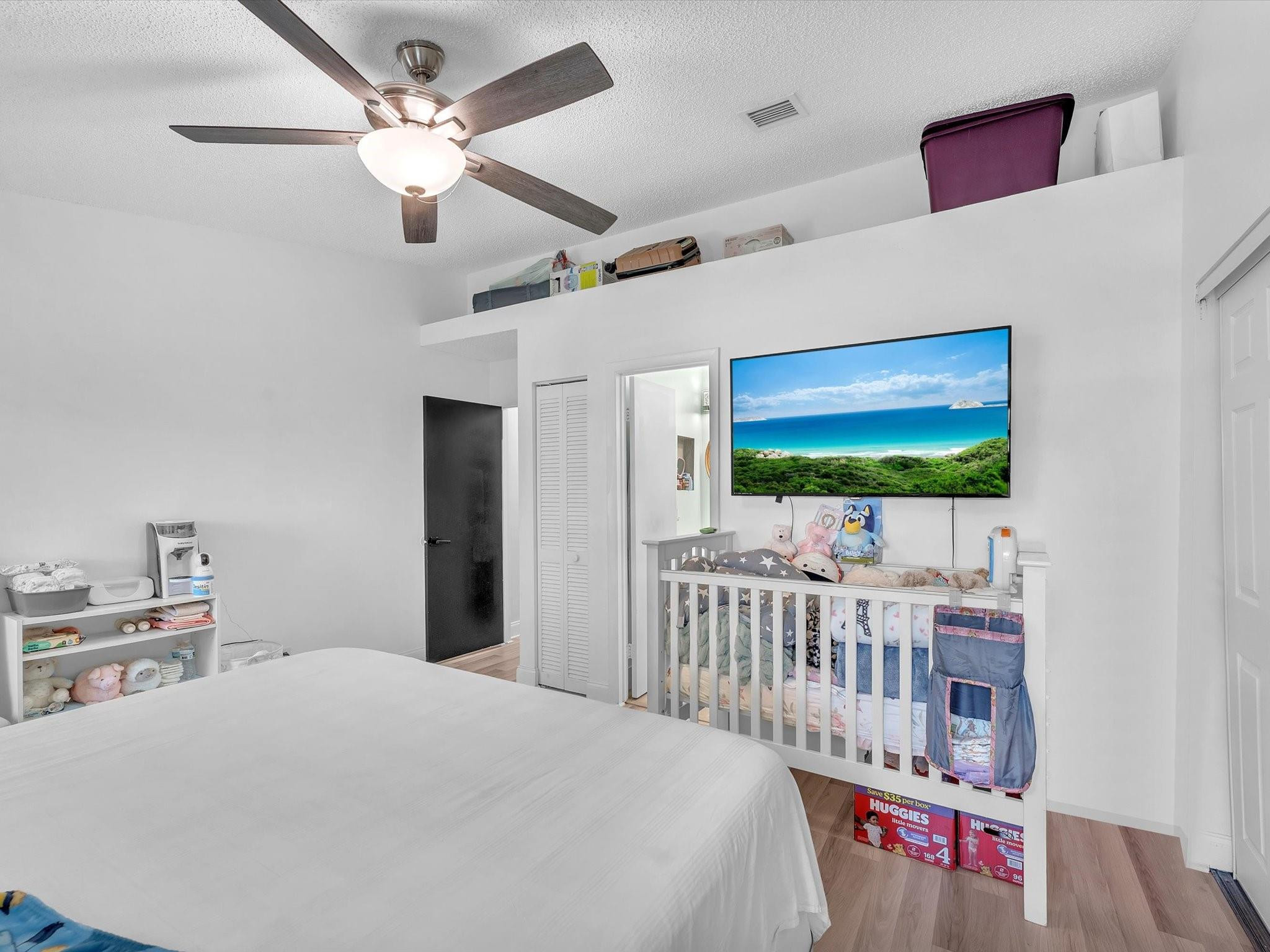 9831 Riverside Drive Coral Springs, FL 33071 - Photo 16 of 27 a bedroom with furniture a flat screen tv and a chandelier