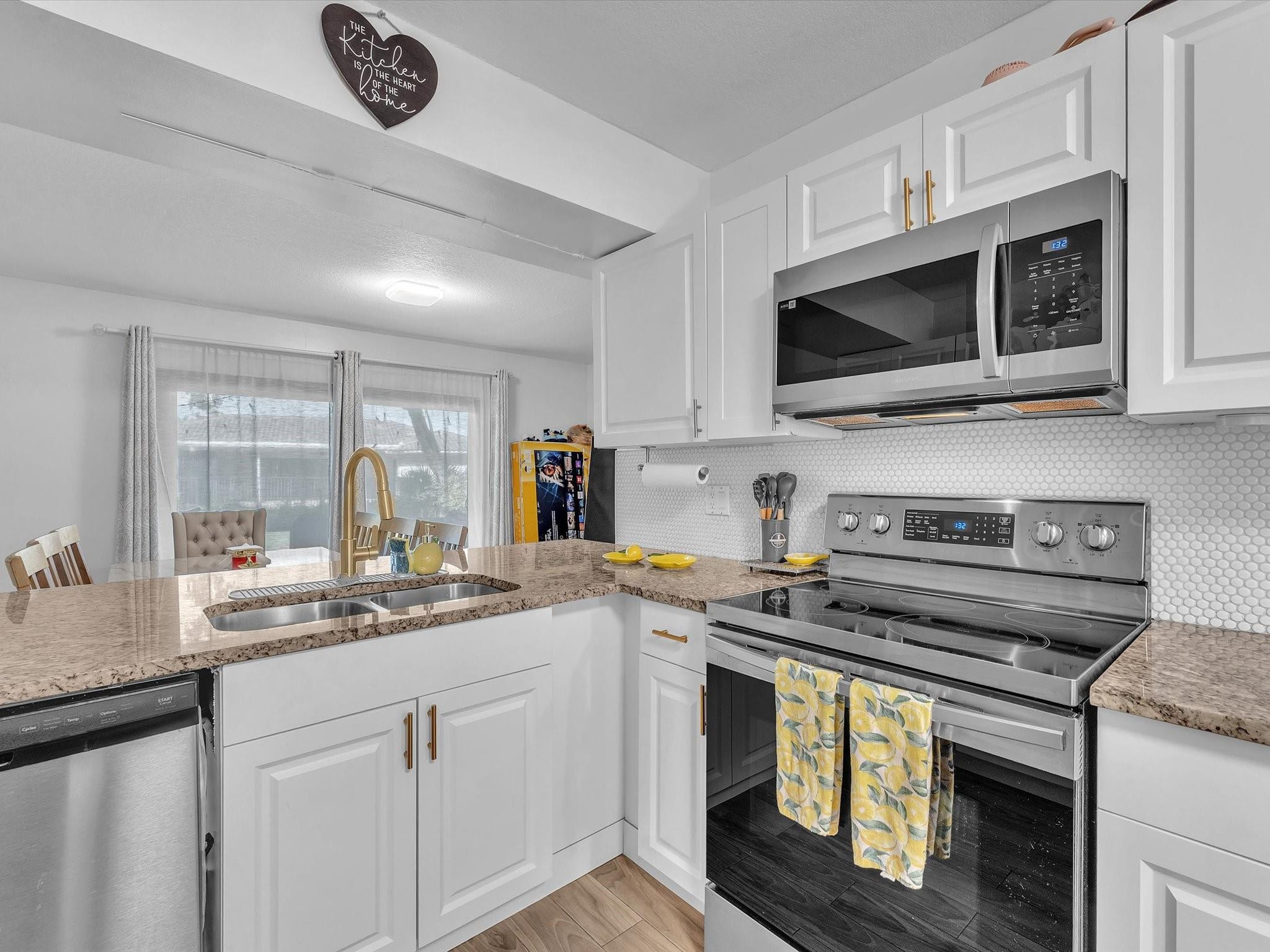 9831 Riverside Drive Coral Springs, FL 33071 - Photo 4 of 27 a kitchen with stainless steel appliances granite countertop a sink a stove a microwave and wooden cabinets