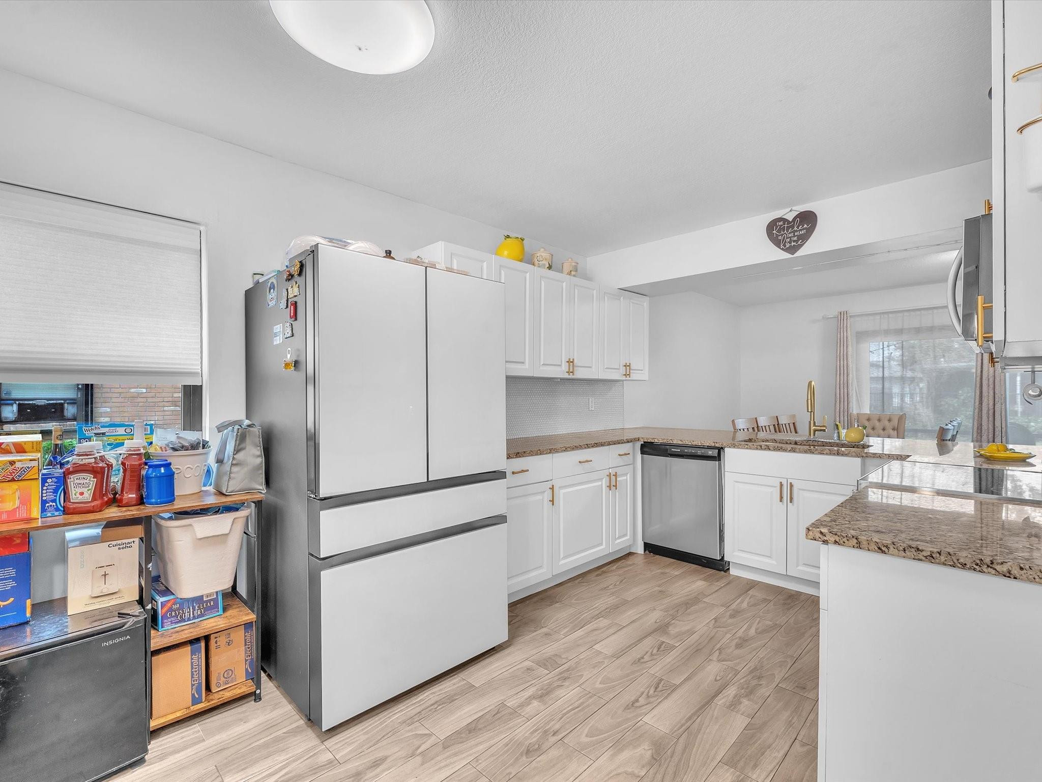 9831 Riverside Drive Coral Springs, FL 33071 - Photo 6 of 27 a kitchen with granite countertop a white refrigerator a sink dishwasher and white cabinets with wooden floor