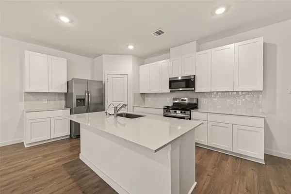 a kitchen with a sink a microwave a refrigerator and cabinets