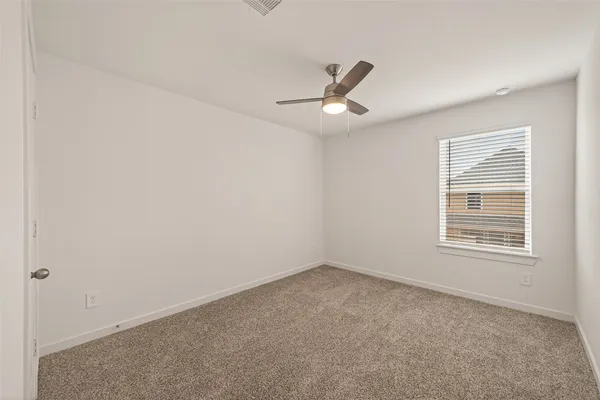 an empty room with a window and ceiling fan