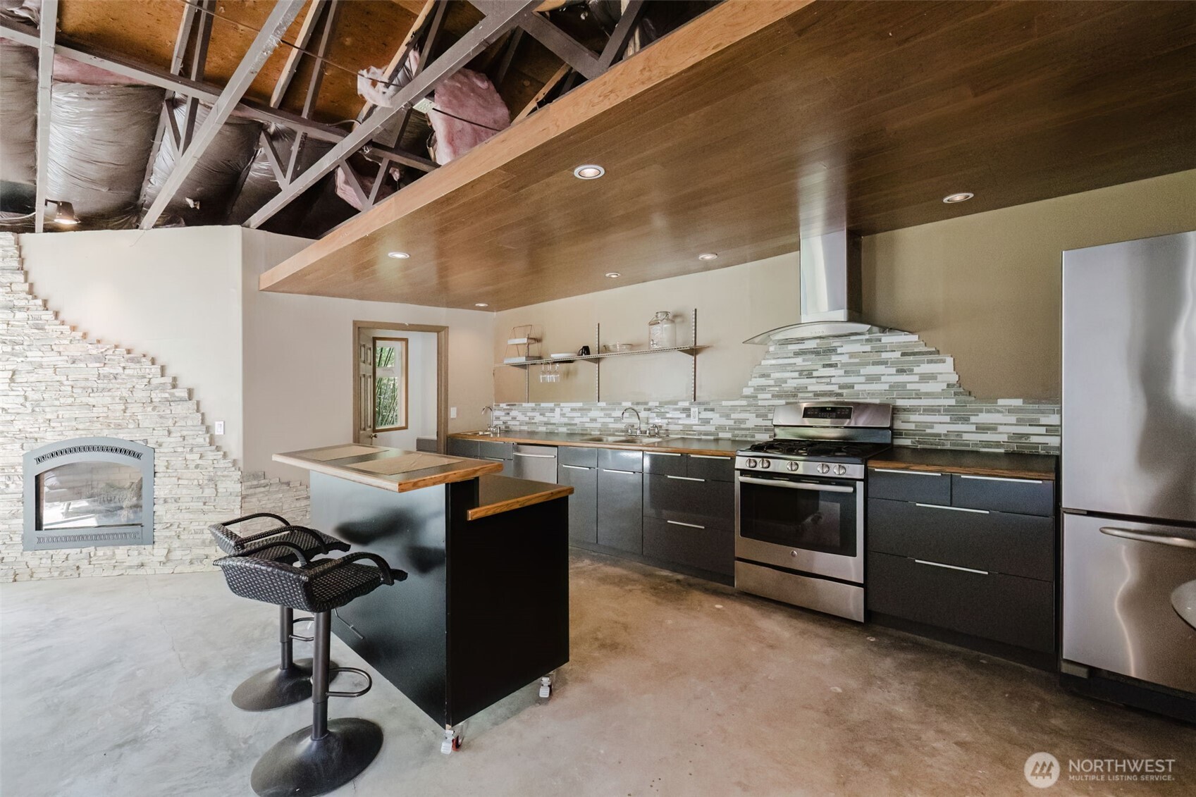 105 Schoolhouse Road Brinnon, WA 98320 - Photo 17 of 39 a kitchen with stainless steel appliances kitchen island granite countertop a table chairs in it and wooden floors