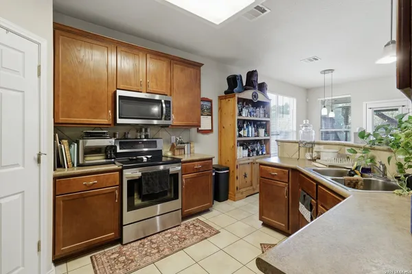 a kitchen with stainless steel appliances granite countertop a stove top oven a sink dishwasher a dining table and chairs with wooden floor