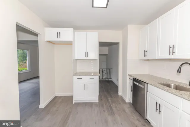 a kitchen with granite countertop white cabinets and stainless steel appliances