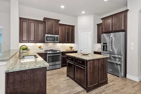 a kitchen with granite countertop a refrigerator and stove