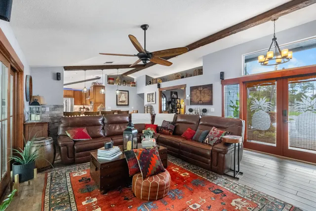 a living room with furniture a ceiling fan and a large window