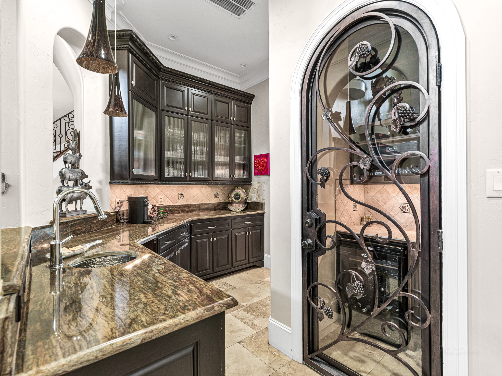 4614 Inker Street Houston, TX 77007 - Photo 19 of 36 This butler’s pantry features dark wood cabinetry, granite countertops, and a decorative wrought iron door leading to a wine storage/bar area. It is conveniently located near the formal dining room and kitchen for entertaining.