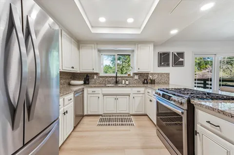 a kitchen with stainless steel appliances granite countertop a stove a sink and a refrigerator