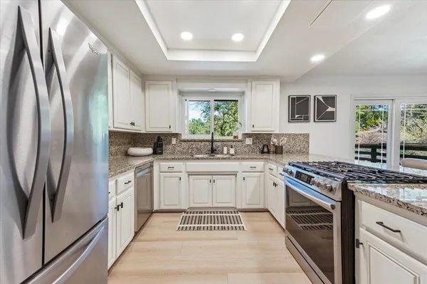 a kitchen with stainless steel appliances granite countertop a stove a sink and a refrigerator