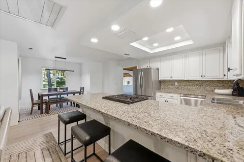 a kitchen with granite countertop kitchen island sink stove and white cabinets