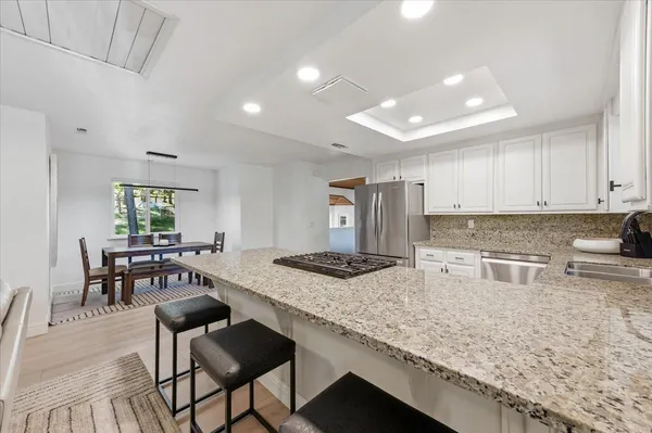 a kitchen with granite countertop kitchen island sink stove and white cabinets