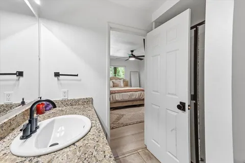 a en suite bathroom with a granite countertop sink and a mirror