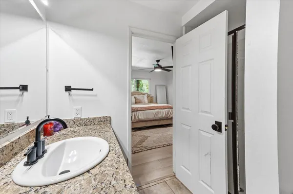 a en suite bathroom with a granite countertop sink and a mirror