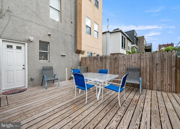 a view of a roof deck with table and chairs wooden floor and fence
