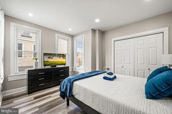 a bedroom with a bed and a flat tv screen on dresser
