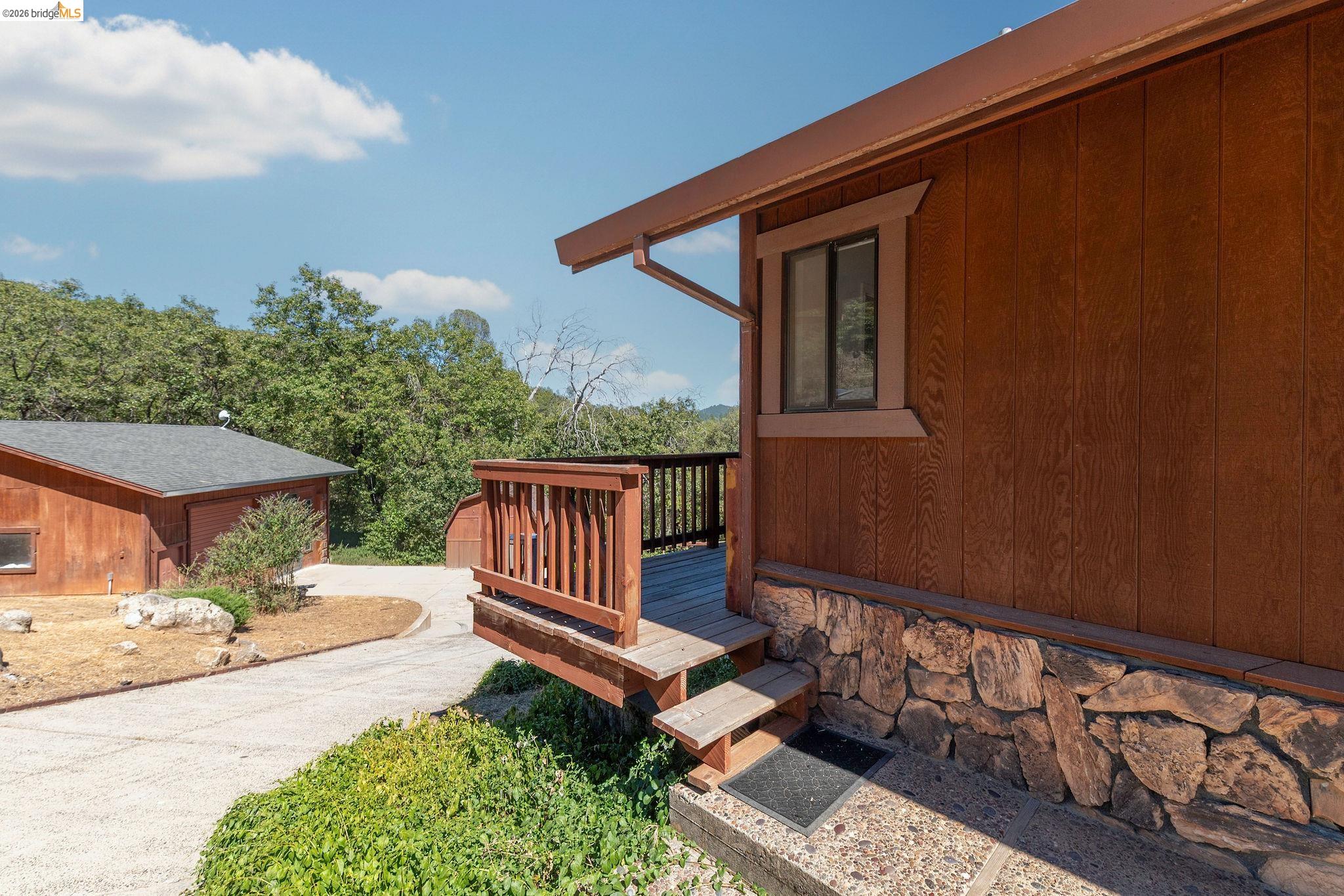 22963 Robertson Ranch Road Sonora, CA 95370 - Photo 72 of 90 Wood-sided exterior featuring a stone foundation and a private deck with wooden railings