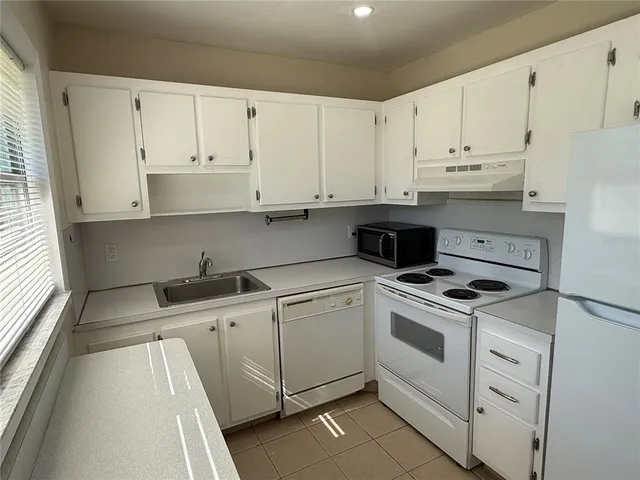 a kitchen with granite countertop white cabinets and white appliances