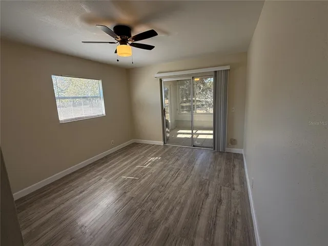 an empty room with wooden floor and windows