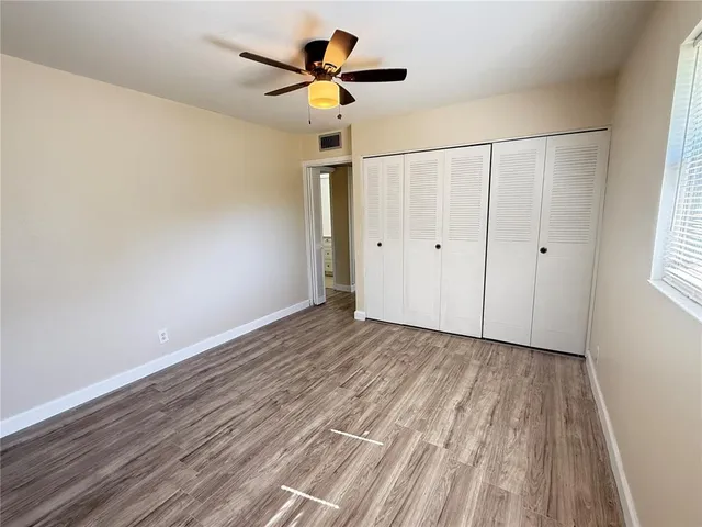 a view of a livingroom with a ceiling fan wooden floor and window