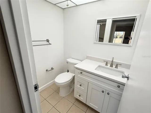 a bathroom with a granite countertop toilet sink and mirror