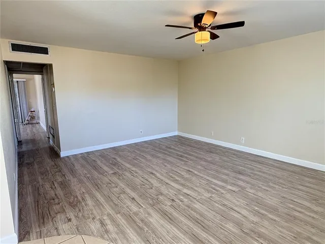 a view of a room with wooden floor and a ceiling fan
