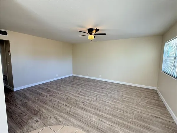 a view of a room with wooden floor and a ceiling fan