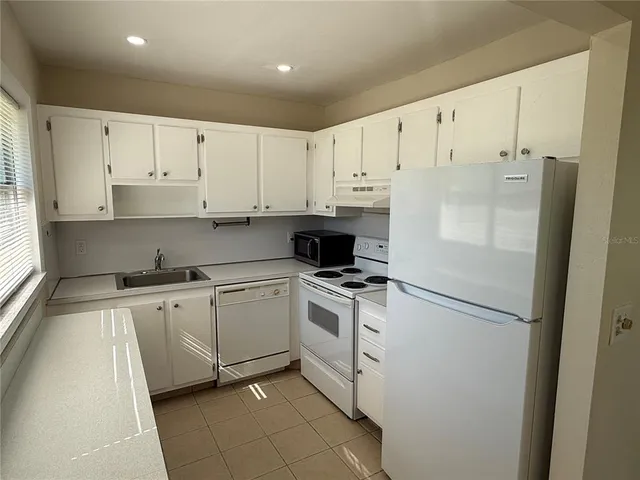 a kitchen with cabinets stainless steel appliances and a refrigerator