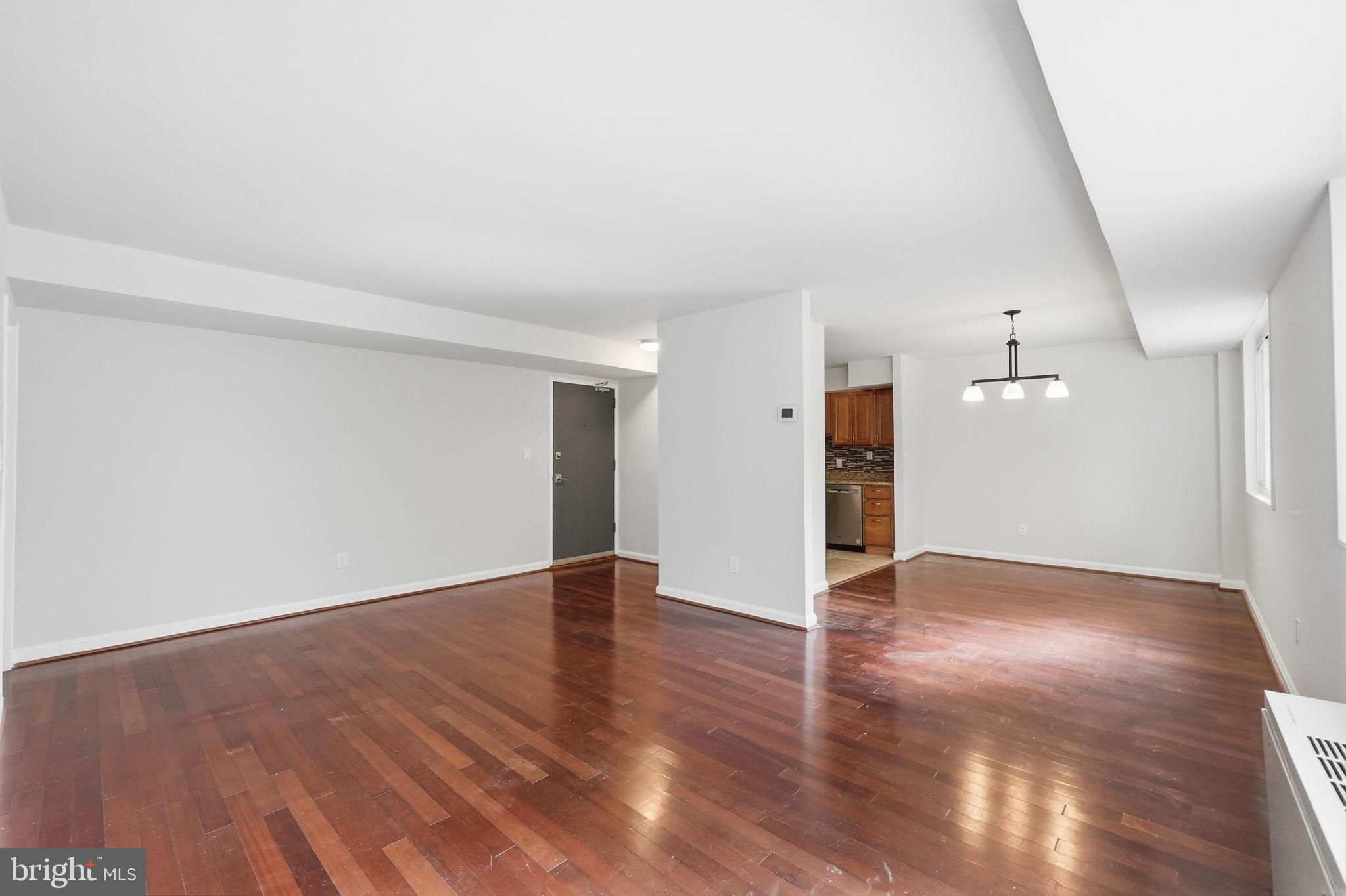 95 East Wayne Avenue, Unit 101 Silver Spring, MD 20901 - Photo 13 of 20 a view of an empty room with wooden floor and a window