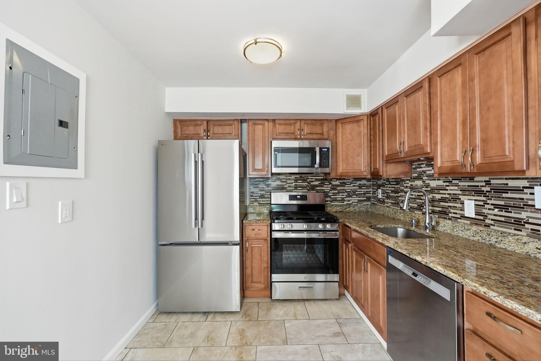 95 East Wayne Avenue, Unit 101 Silver Spring, MD 20901 - Photo 5 of 20 a kitchen with stainless steel appliances granite countertop a refrigerator stove and sink