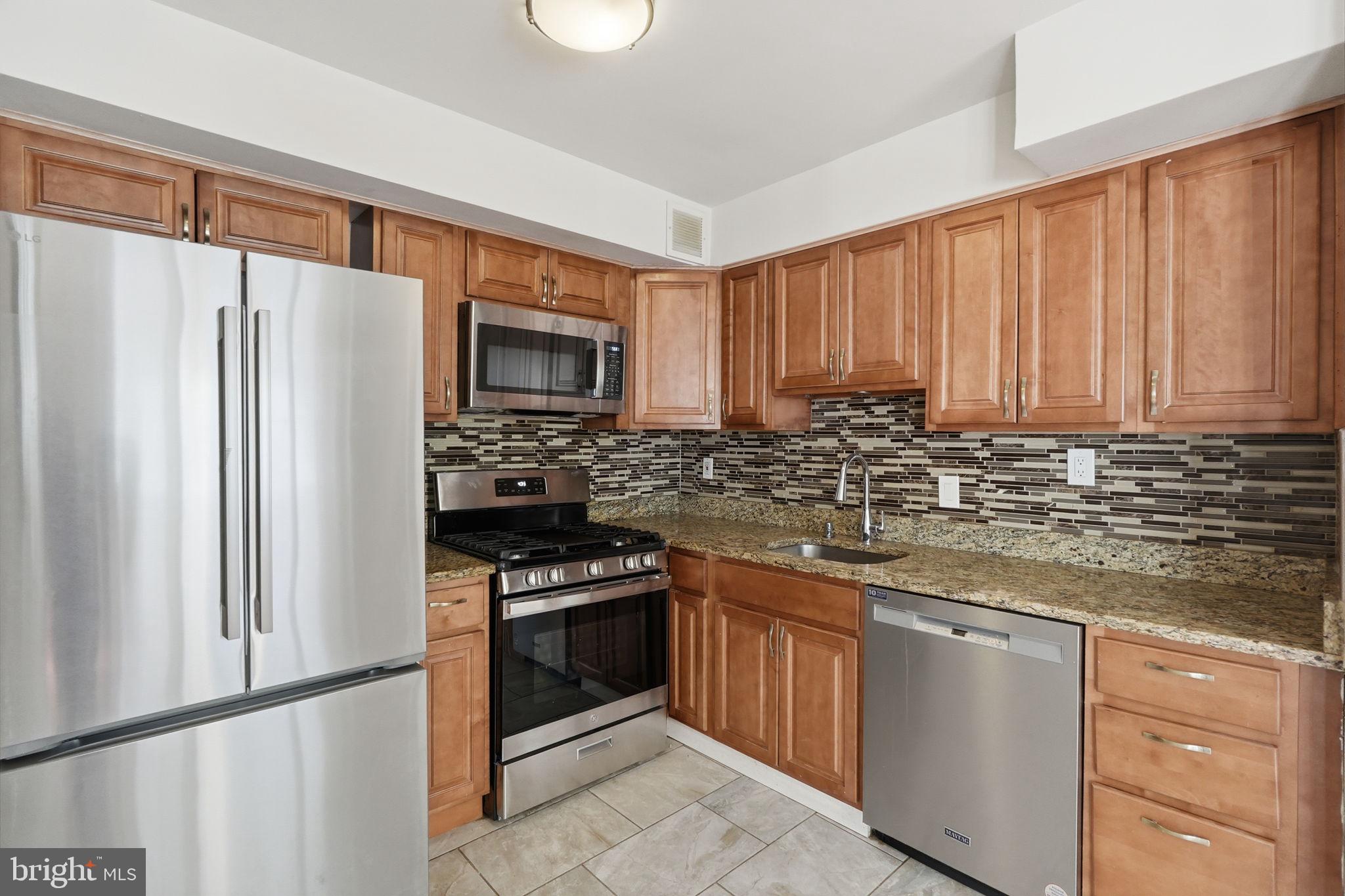 95 East Wayne Avenue, Unit 101 Silver Spring, MD 20901 - Photo 6 of 20 a kitchen with stainless steel appliances granite countertop a refrigerator stove a sink and dishwasher