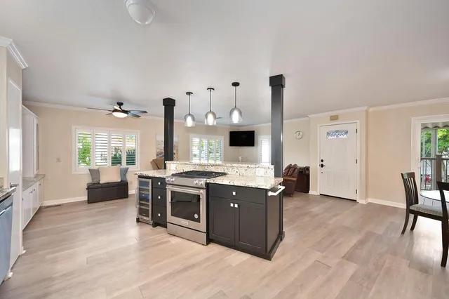 a kitchen with granite countertop a refrigerator a sink a stove and white cabinets