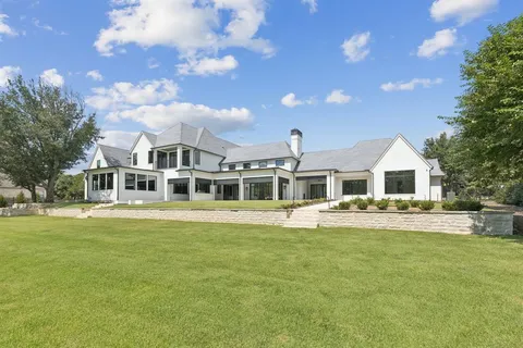 an aerial view of a house with swimming pool and large trees