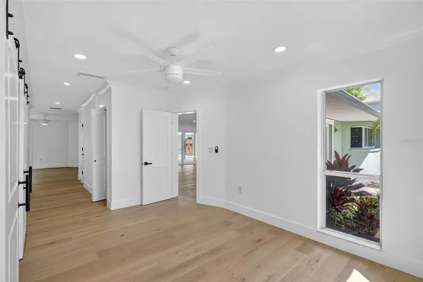 a view of empty room with wooden floor and fan