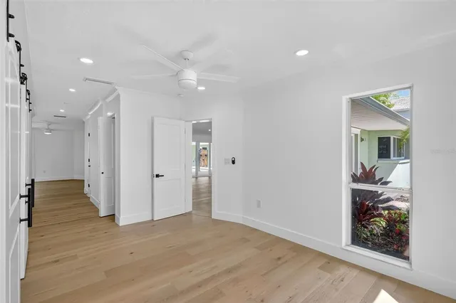 a view of empty room with wooden floor and fan
