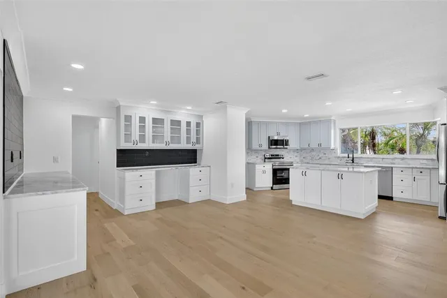 a view of a kitchen with an empty room and wooden floor
