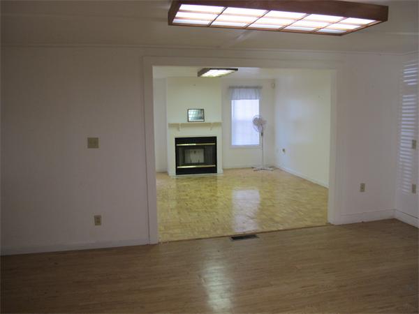 16 Butler Street Wareham, MA 02532 - Photo 2 of 7 an empty room with wooden floor fireplace and windows