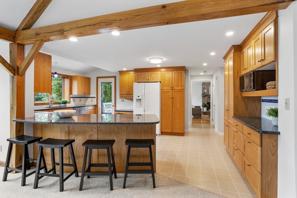 444 Middle Road Boxborough, MA 01719 - Photo 10 of 42 a kitchen with stainless steel appliances kitchen island granite countertop a table chairs and a refrigerator