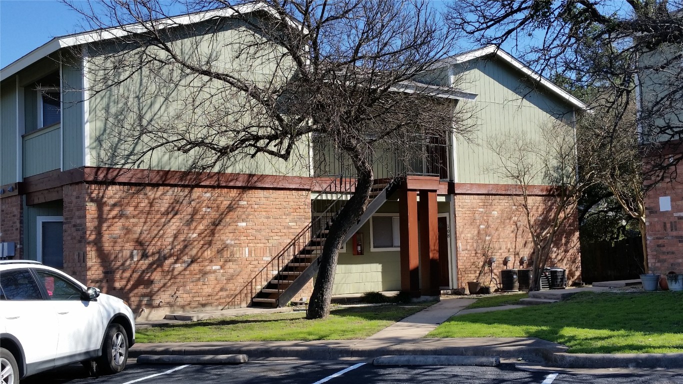 6809 West Gate Boulevard, Unit 203 Austin, TX 78745 - Photo 2 of 12 View of front of house with brick siding, stairs, uncovered parking, and a front lawn