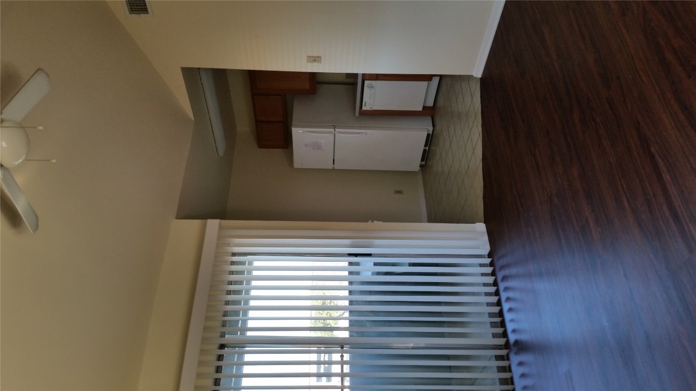 6809 West Gate Boulevard, Unit 203 Austin, TX 78745 - Photo 4 of 12 Unfurnished living room with dark wood-style flooring, vaulted ceiling, and ceiling fan