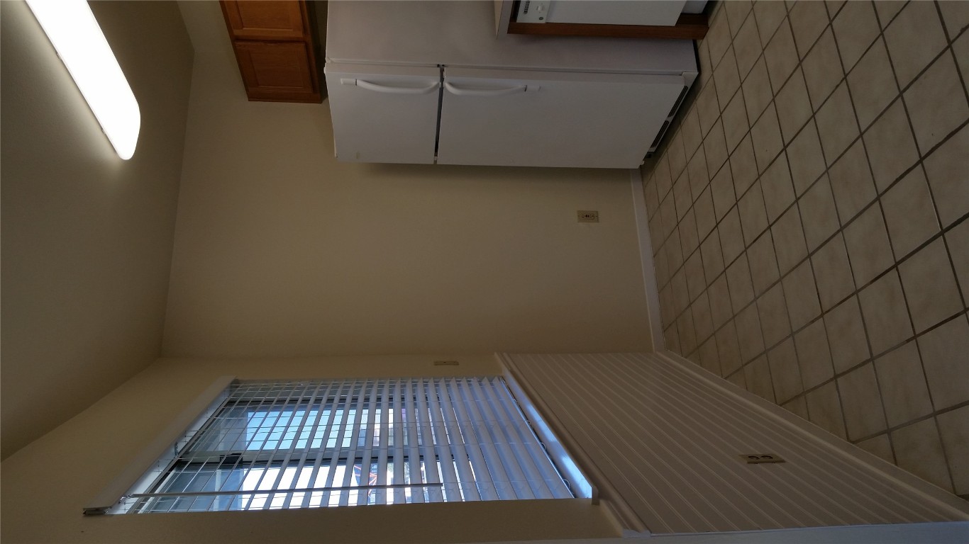 6809 West Gate Boulevard, Unit 203 Austin, TX 78745 - Photo 7 of 12 Kitchen with freestanding refrigerator, brown cabinets, and light tile patterned floors