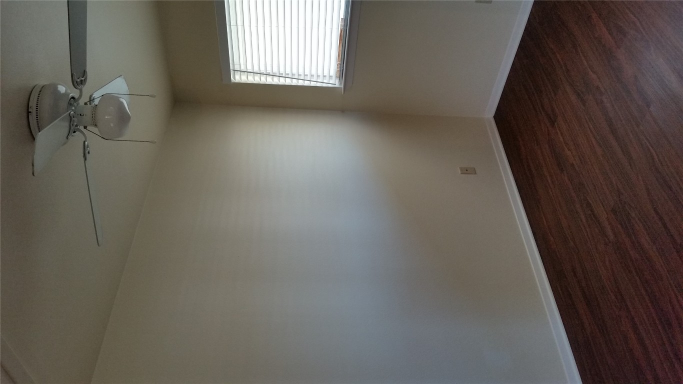 6809 West Gate Boulevard, Unit 203 Austin, TX 78745 - Photo 10 of 12 Empty room with dark wood finished floors and ceiling fan