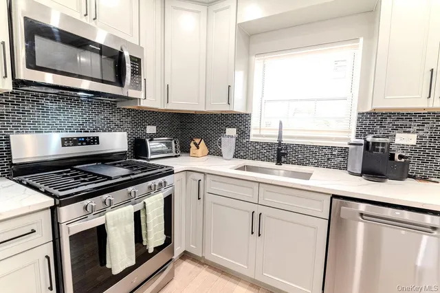 a kitchen with stainless steel appliances a dining table chairs refrigerator and microwave