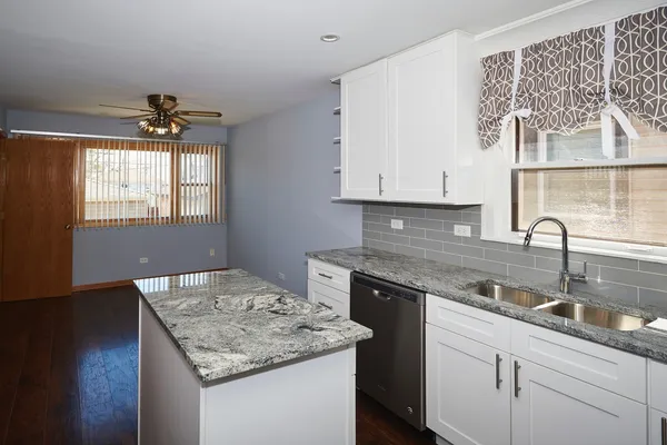 a kitchen with granite countertop a sink stainless steel appliances white cabinets and a window