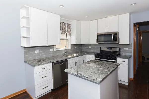 a kitchen with granite countertop a sink stove and microwave