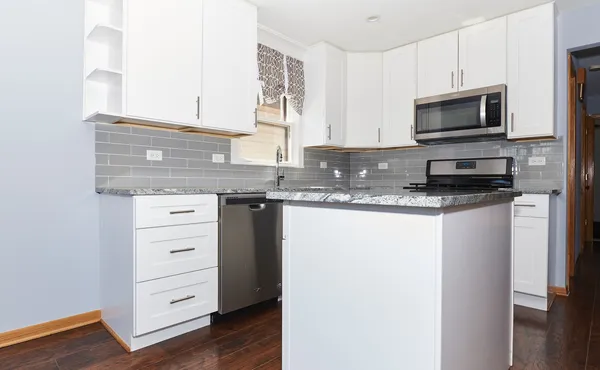a kitchen with granite countertop a stove microwave and a refrigerator