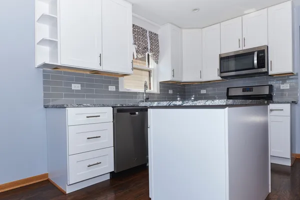 a kitchen with granite countertop a sink and a microwave